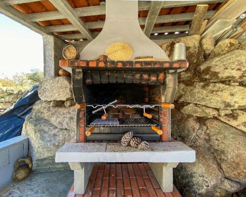 an outdoor pizza oven with a pine cone on a table at Encosta do Sol in Canas de Senhorim