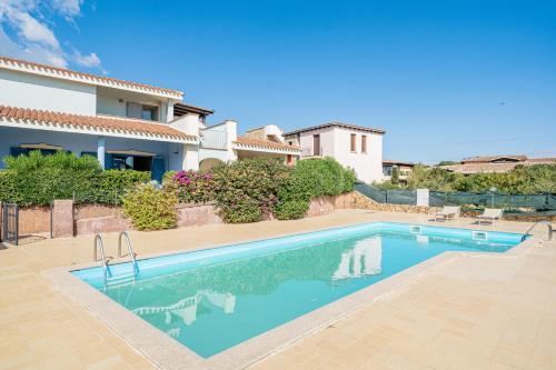 a swimming pool in front of a house at Apartments in Residence with swimming pool in Cala Girgolu in Monte Petrosu