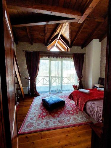 a bedroom with a bed and a large window at Petradi Residence @ Agoriani-Parnassus in Eptalofos