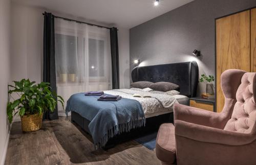 a bedroom with a bed and a chair at Apartamenty 73 in Ustrzyki Dolne
