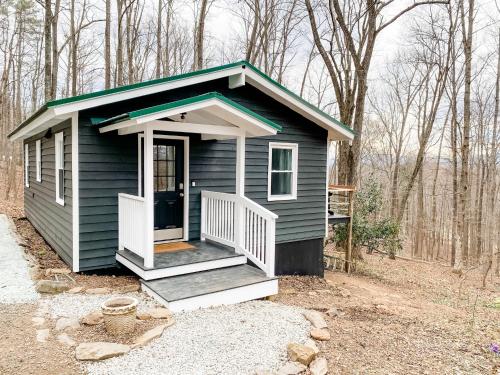 a blue tiny house with a porch in the woods at Mountain Retreat Nesteled in the Virginia Foothills in Charlottesville