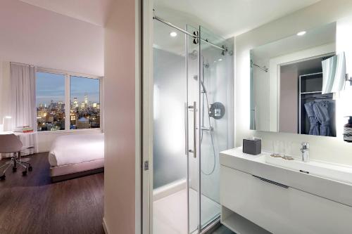 a bathroom with a shower and a sink and a bed at INNSiDE by Meliá New York Nomad in New York