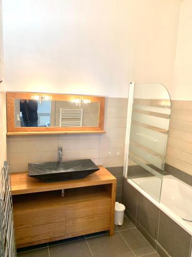 une salle de bain avec un lavabo, un miroir et une baignoire dans l'établissement Le Relais Dunois de Napoléon, à Châteaudun