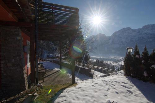 a sun shining over a snow covered hill with a house at Ferienwohnungen BergArt in Iselsberg