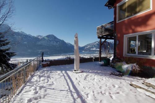 a snow covered porch of a house with mountains in the background at Ferienwohnungen BergArt in Iselsberg