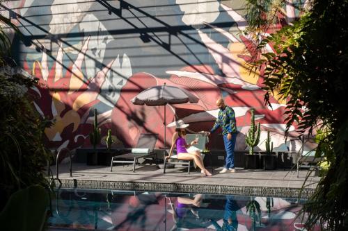 a man and a woman sitting under an umbrella next to a pool at Hotel Hotel - Member of Design Hotels in Lisbon