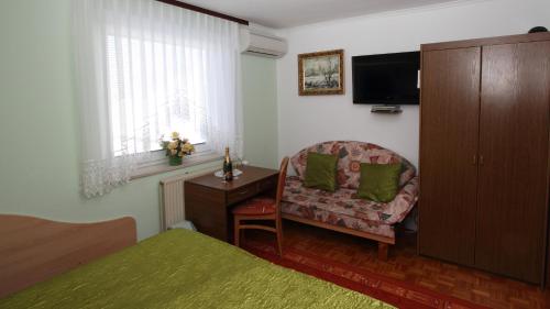 a bedroom with a bed and a chair and a television at Rooms & Apartments Jana in Cerklje na Gorenjskem