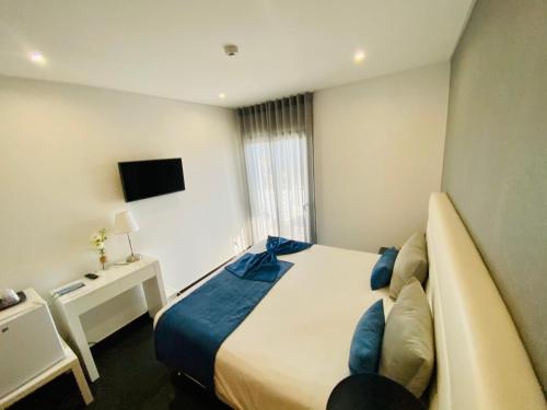 a hotel room with a bed and a television at Sunfield Guest House - Only Adults in Albufeira