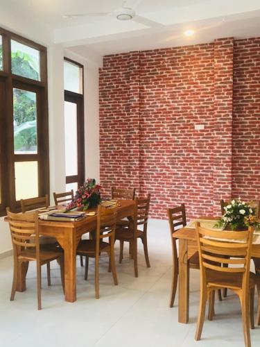 a dining room with wooden tables and chairs and a brick wall at SaDev Lake Villa Bandaragama in Bandaragama