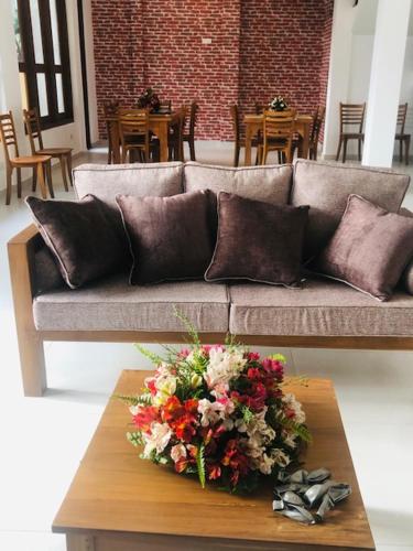 a couch with a bouquet of flowers on a coffee table at SaDev Lake Villa Bandaragama in Bandaragama