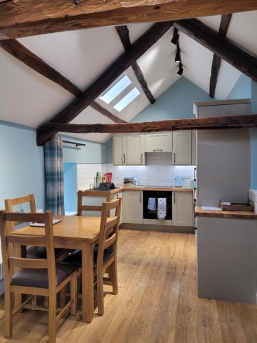 The Granary في Llanddeiniol: مطبخ وغرفة طعام مع طاولة وكراسي خشبية