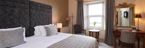 a bedroom with a bed and a desk and a window at Royal Golf Hotel in Dornoch