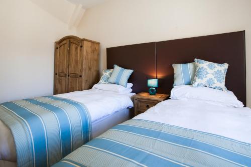a bedroom with two beds and a wooden headboard at White Swan Cottage in Alnwick