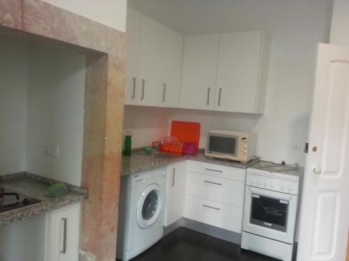 a kitchen with a washing machine and a microwave at Lisbon Gambori Hostel in Lisbon