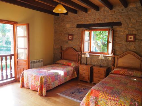 a bedroom with two beds and a stone wall at Casa Rural La Roza 2 in Buelles