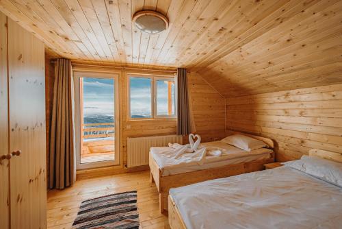 a bedroom with two beds and a large window at Cabana Dominic in Mărişel