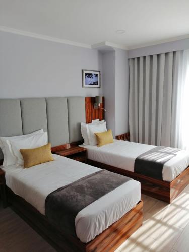 a hotel room with two beds and a window at Memória Charming House in Angra do Heroísmo