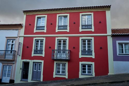 a red building with white windows and balconies at Memória Boutique Hostel in Angra do Heroísmo