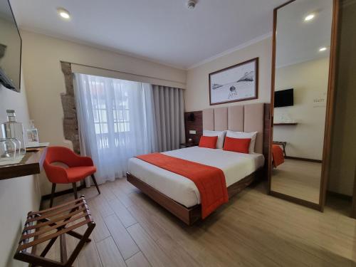 a hotel room with a bed and a chair and a mirror at Memória Charming House in Angra do Heroísmo