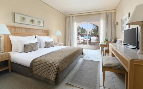 a hotel room with a large bed and a television at Jaz Makadi Star & Spa in Hurghada