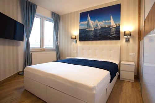 a bedroom with a large white bed with sails on the wall at Apartamenty Na Fali in Darłówko