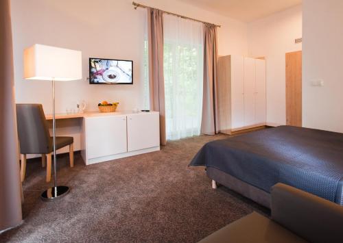 ウストロニエ・モルスキエにあるBorgataのベッド、デスク、テレビが備わるホテルルームです。