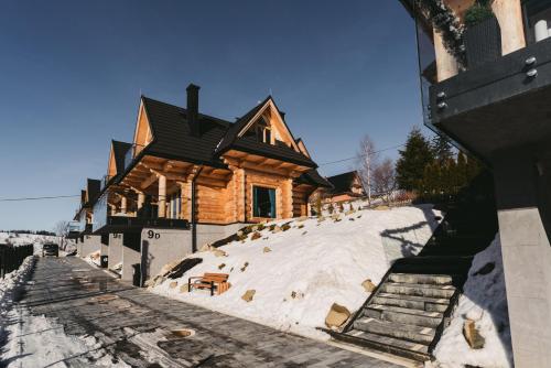 a log cabin in the snow in front of a house at Osada Bachledzki Wierch Odkryj Zakopane in Zakopane