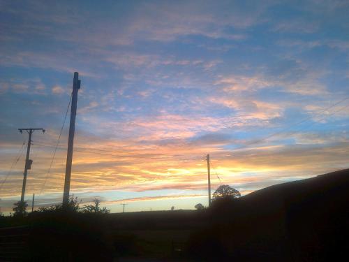 a sunset with two telephone poles and a cloudy sky at Courtbrook Farm in Exeter