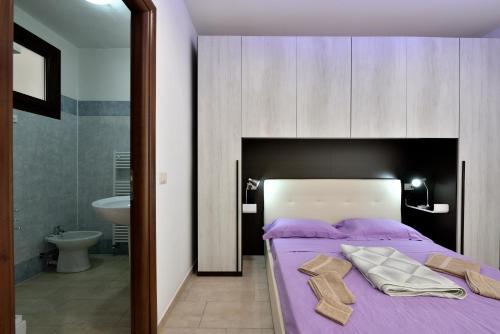 LoceriにあるAlbergo Diffuso Antica Posadaのベッドルーム1室(紫のシーツが敷かれたベッド1台付)、バスルーム1室が備わります。