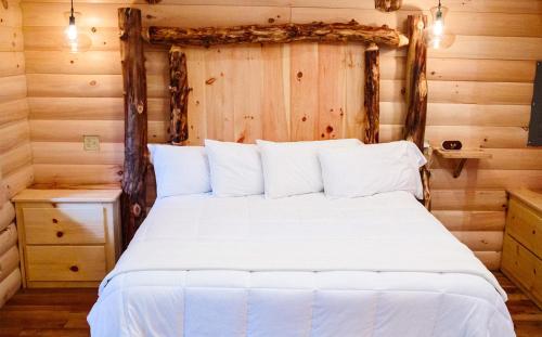 1 dormitorio con 1 cama blanca en una cabaña de madera en Cricket Hill Treehouse D by Amish Country Lodging en Millersburg