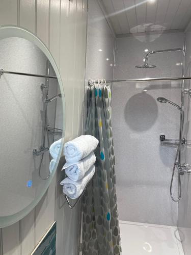 a bathroom with a shower and a mirror and towels at Famau Cabins Gwel Y mynudd in Cilcain