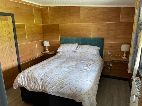 a bedroom with a large bed with wooden walls at Famau Cabins Gwel Y mynudd in Cilcain