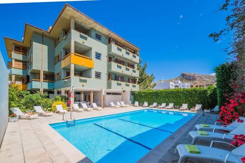 a swimming pool in front of a building with lounge chairs at Apartamento Bressol 3ºd in Port de Pollensa