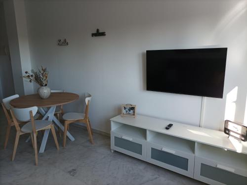 sala de estar con mesa y TV en la pared en IJD apartments 119 PARKING GRATIS Y PISCINA, en Bormujos