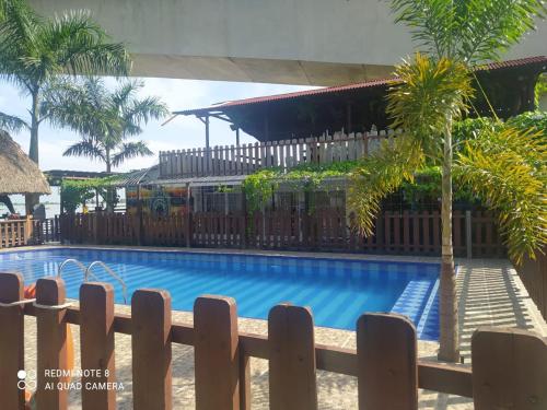 a wooden fence next to a swimming pool with palm trees at Hotel Campestre Maguey in Mangue