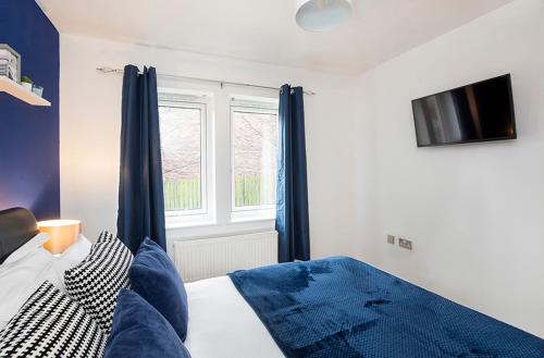 a bedroom with a bed with blue curtains and a tv at Liber House in York