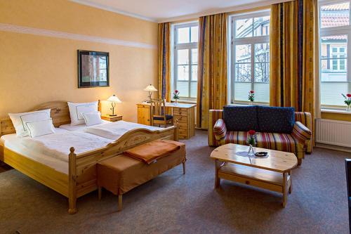 a hotel room with a large bed and a couch at Altenceller Tor, Hotel & Restaurant in Celle