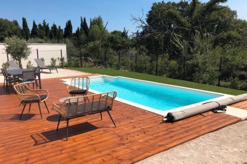einen Pool mit Stühlen und einem Tisch auf einer Holzterrasse in der Unterkunft House With Piscine At The Gates Of Avignon in LʼIsle-sur-la-Sorgue