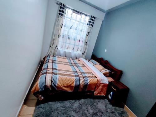 um pequeno quarto com uma cama e uma janela em ASHÉ em Naivasha