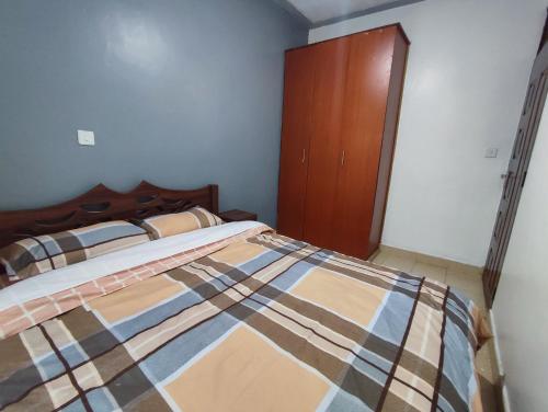 um quarto com uma cama e um armário de madeira em ASHÉ em Naivasha