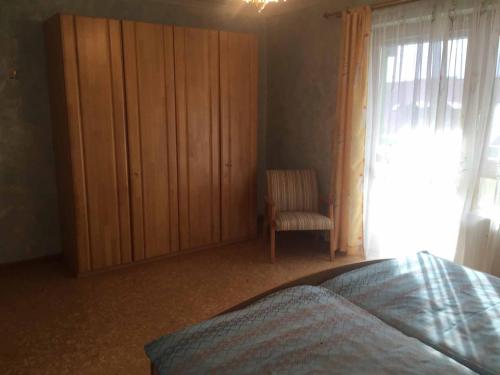 a bedroom with a bed and a cabinet and a chair at Appartements Gillmeier Herta in Bad Griesbach