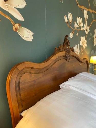 a bed with a wooden head board with flowers on the wall at Maison de l'Aumance in Meaulne