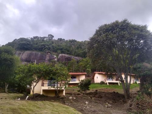a house in front of a mountain with trees at Pousada Pedra Grande in Bueno Brandão