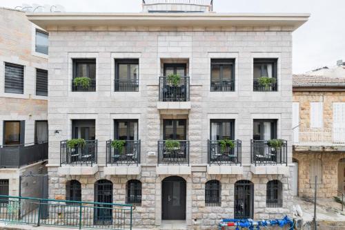 an old brick building with potted plants on the balconies at Mate ALMA - By HOMY in Jerusalem
