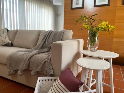 ein Wohnzimmer mit einem Sofa und einer Vase mit Blumen auf dem Tisch in der Unterkunft TOP BEACH HOUSE in Costa da Caparica
