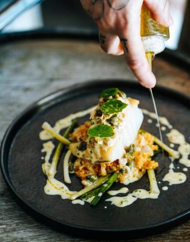 a person holding a piece of food on a plate at The Peacock Inn in Chelsworth