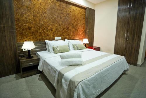 a bedroom with a large white bed and a wall at Hotel Shams Inn in Cochin