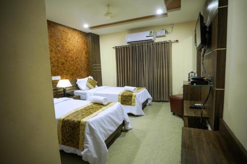 a hotel room with two beds and a television at Hotel Shams Inn in Cochin