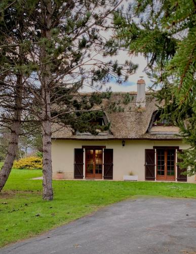 Una casa blanca con un árbol delante. en Maison traditionnelle Normande avec piscine, en Hotot-en-Auge