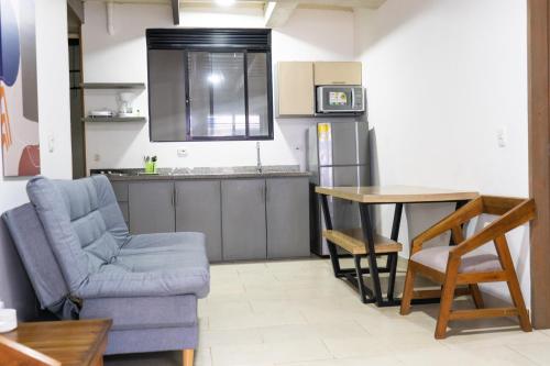 a living room with a chair and a table and a kitchen at M1145 Aparta Loft in Pereira